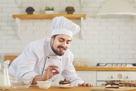A male pastry chef works decorating a cake on a kitchen bakery.の写真素材