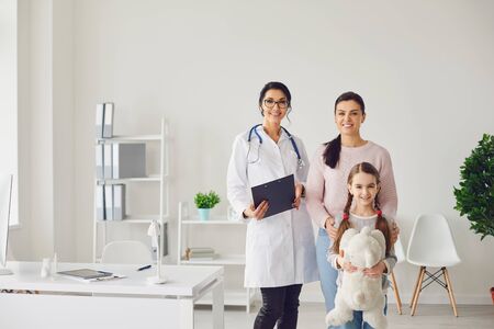 Happy family at the doctors visit at the office. Family doctor standing with smiling family at the clinic.の写真素材
