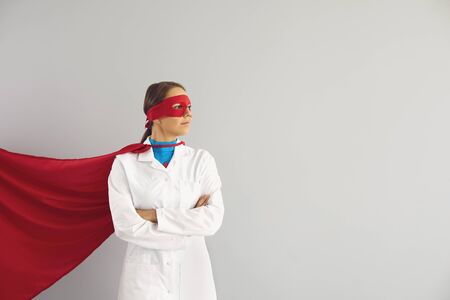 Confident female doctor superhero over gray background. Medical protection of human health.の写真素材
