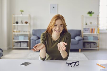 Online video blog. Beautiful redhead girl looking at the camera says video blog call. A young woman...
