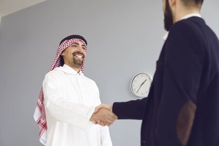 Handshake of arabic and european businesspeople. Businessman hands makes a handshake in the office. The conclusion of the contract by business people.の写真素材