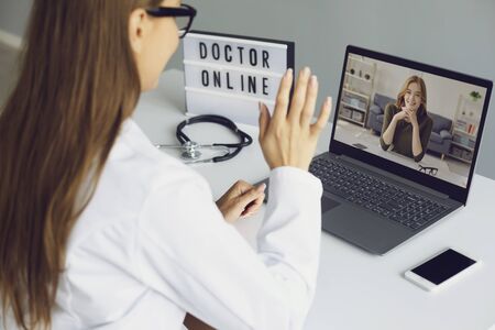 Doctor online. A young woman has an online video consultation with a doctor at the clinic office. A medical therapist speaks with a patient to a girl using a web chat application. Telemedicine. Medical care insurance diagnose symptom analysis remotely.の写真素材