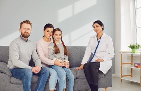Doctor pediatrician woman in a white coat with family in the room sitting not on the couch.の写真素材