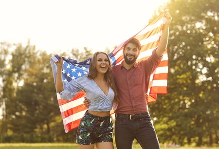 Patriotic celebration of independence of America on July 4. Happy couple with america flag celebrating independence day at sunset.の写真素材