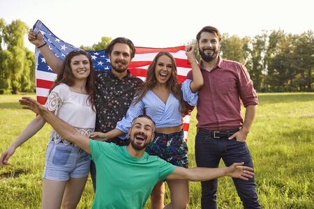 Patriotic celebration of independence of America on July 4. Friends smiling with america flag celebrate usa independence day.の写真素材