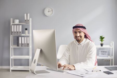 Arab man working analyzing typing while sitting at a table with a computer in the office.の写真素材