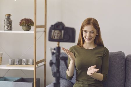 Blogger vlogger girl speaks to the camera while sitting on a sofa in a room at home. A young...