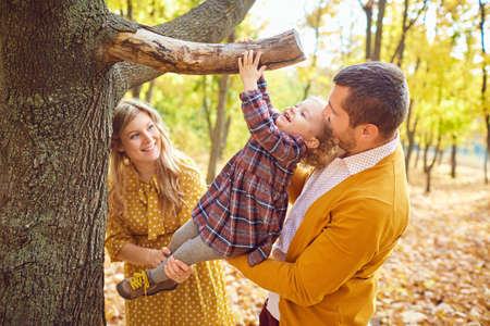 Happy family smiling playing in the park in the fall.の写真素材