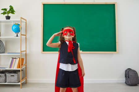 Children at school. Schoolgirl superhero fun laughing in a school class. Education study teaching at...