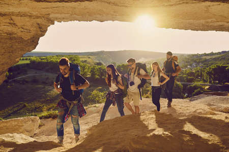 Friends tourists with backpacks walk along the route in a cave in the mountains in nature. Hike....