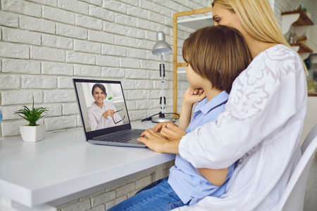 Online medicine. Mother and her little son communicating with pediatrician on laptop from home. Child and parent talking to doctor on webの写真素材