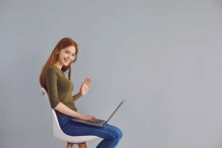 Online communication. Young red haired girl talking to family, friends or colleagues on laptop,...