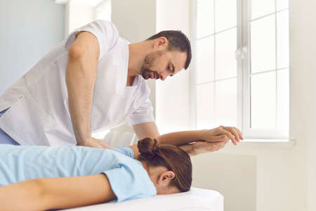 Serious doctor doing medical massage to female patient. Osteopath, physiotherapist or alternative...