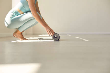 Low section of fit woman in activewear getting ready for regular workout. Ground level side view of...
