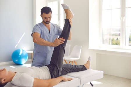 Young male athlete getting professional help in medical center after sports injury. Serious...