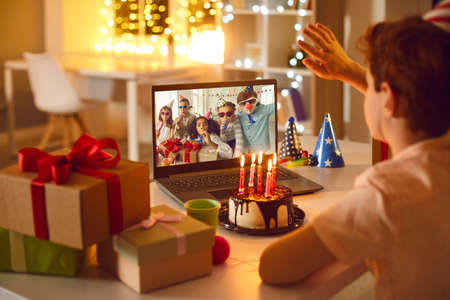 Birthday online. Children remotely wish their friend happy birthday using video call chat conference laptop.の写真素材