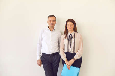 Positive man and woman business partners office workers standing with documents and looking at...