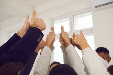 Success, thumbs up gesture, teamwork concept. Hands of mixed race group business partners raised up and showing thumbs up sign meaning successful cooperation and project developmentの写真素材
