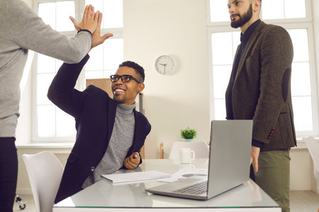 Business agreement, deal, successful project concept. Young smiling multi ethnic business partners shaking hands after successful negotiations or project realization in officeの写真素材