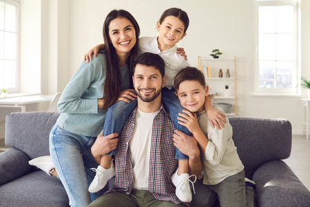 Happy mother, father and cute children on sofa in the living-room. Webcam portrait of smiling young...