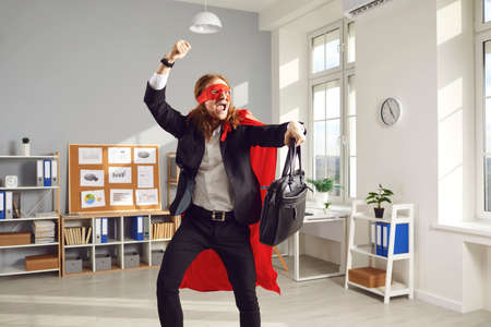 Joyful superhero businessperson or corporate employee dancing and fooling around. Funny goofy young...