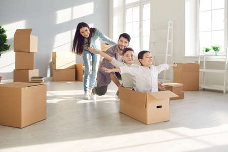 Parents and children moving in. Husband and wife with their children, who are sitting in a cardboard...