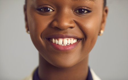 Headshot portrait of happy glad pretty young black woman with nude makeup, gap between upper front teeth and charming toothy smile. Human face, womens beauty, peoples appearance, dental care conceptの写真素材
