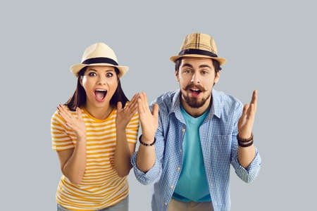 Close up portrait of a surprised married couple who found cheap plane tickets for vacation. Shocked man and woman with open mouth screaming with pleasure on a gray background. Banner. Place for text.の写真素材