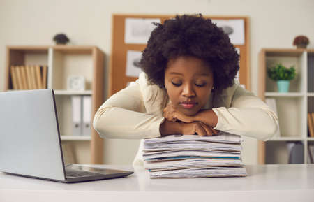 Tired african american woman office worker freelancer sleeping leaned chin on paperwork finance...