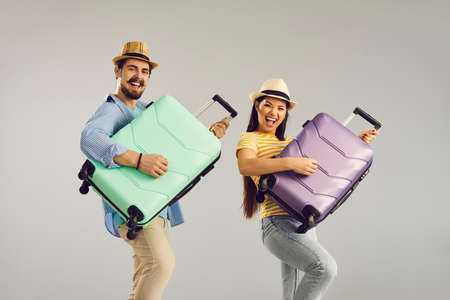 Travel, vacation on holiday, happiness and satisfaction people emotion. Happy overjoyed funny couple traveler tourist having fun playing on suitcase like guitar studio shot on grey backgroundの写真素材