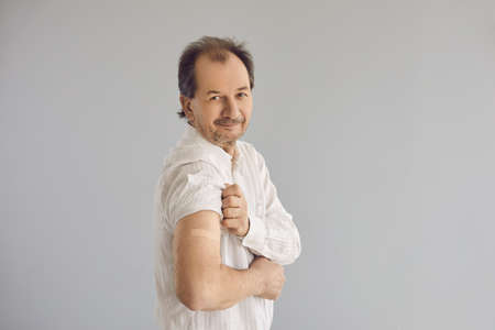 Portrait of senior man after getting vaccine. Happy mature male patient on light gray background...