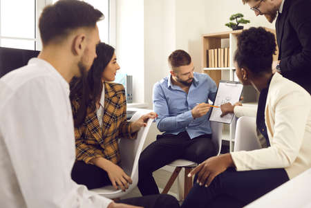 Collaborative process, briefing, project discussion. Male entrepreneur executive manager explaining business plan to boss and multicultural diverse skilled team during brainstorming meeting in officeの写真素材
