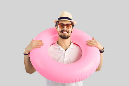 Portrait of a cheerful man with a pink inflatable circle around his neck who is ready for summer...