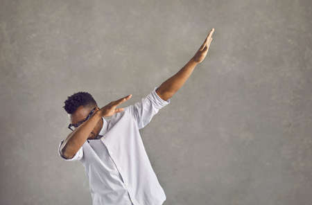 Happy handsome young black man with Afro hairstyle dancing dub against gray stone street wall. Funky...