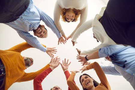 Team of happy diverse people standing in circle, joining hands, smiling and feeling united like one...