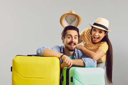 Cheerful wife takes off husband hat and laughing. Happy overjoyed funny Caucasian family couple traveler with luggage bag ready for summer travel holiday vacation studio headshot portraitの写真素材