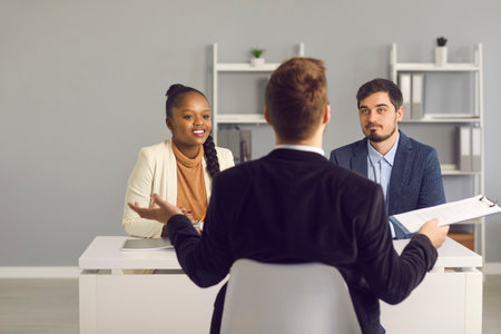 Young married couple listens intently to a bank financial advisor at a meeting in the office. Bank...