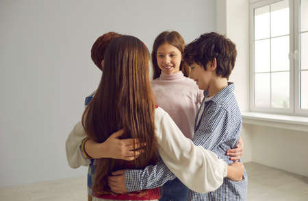 Group of happy school children huddling. Team of four smiling kids hugging each other standing close in circle. Strong community, peer interaction, mutual help, union, connection, friendship conceptの写真素材
