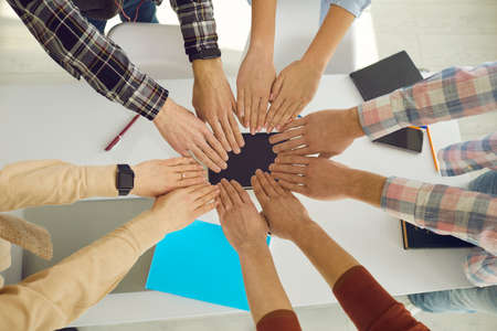 Close up of peoples hands, which they fold together so that the circle is formed as a symbol of unity. Students or a young team of startups go to a common goal. Concept of teamwork. Top view.の写真素材