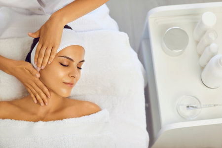 Cosmetologist making professional manual relaxing rejuvenating massage for young womanの写真素材