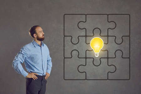 Lightbulb as symbol of business idea. Side profile view intelligent man standing isolated on gray...