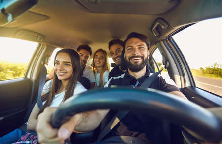 Happy group of people men and women smiling in car, front view. Safety Driving, family travel by car. Friendship conceptの写真素材