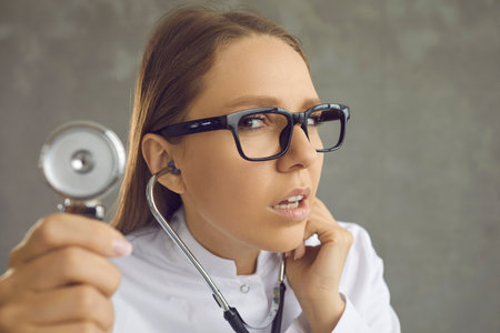 Closeup headshot intern doctor with stethoscope looking at you with serious suspicious funny face...