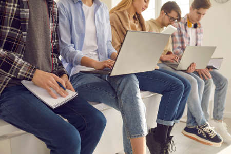 Diverse high school teenager student group studying together doing homework learning lesson preparing for exam using laptop cropped shot. Young people at university campus hall or libraryの写真素材