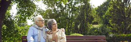 An elderly couple man and women of Asian incursion, happily spend time in a city park, sit on a...