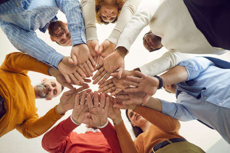 Diverse multiethnic people group of different age and nationality holding hands together. Shot with...