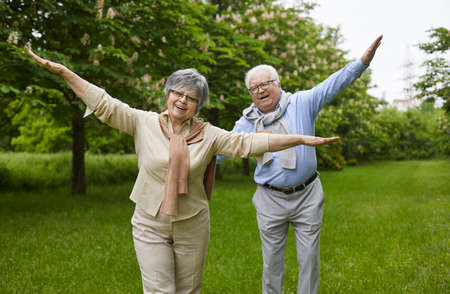 Happy senior couple enjoying life in retirement. Outdoor portrait of cheerful retired mature man and woman playing and having fun in a green summer park or city garden. Lifestyle conceptの写真素材