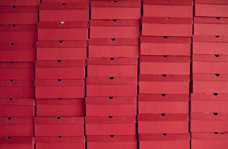 Background of lots of red cardboard package boxes with footwear stacked at a shoe factory warehouse. Business, shoe manufacturing industry, storage, bulk trade, and product distribution conceptsの写真素材