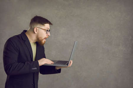 Young man wins a lot of money online. Side view profile portrait funny surprised shocked open mouth...
