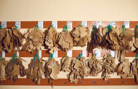 Lots of different real leather details hanging on wooden wall hanger in manufacturing workshop at...